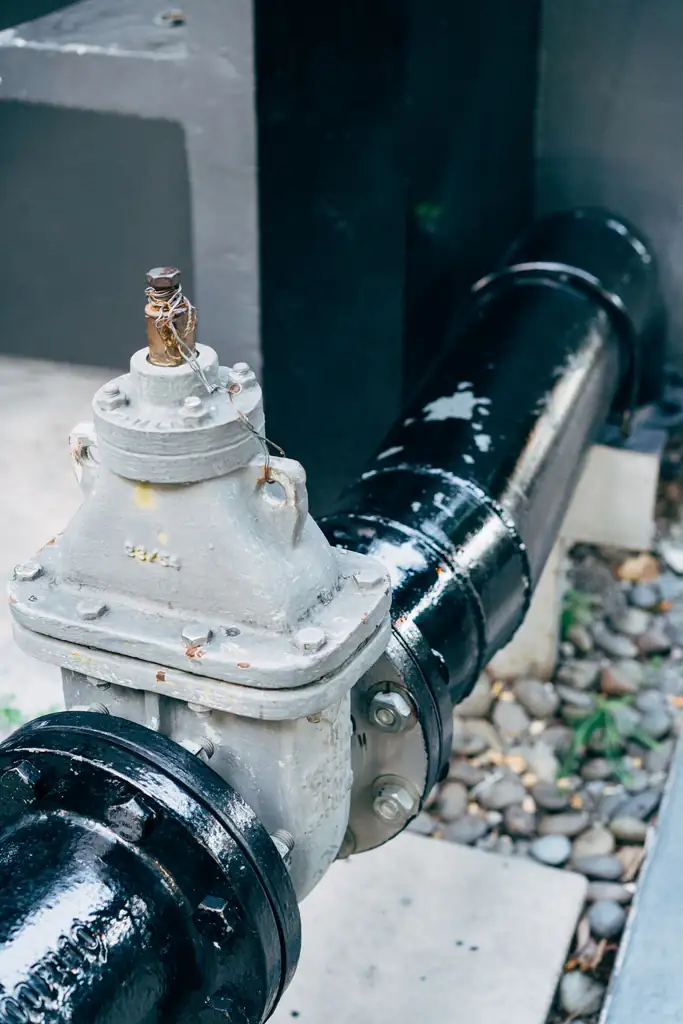 Cutaway view of a sump pit in a basement floor with a submersible pump and discharge pipe rising through the slab